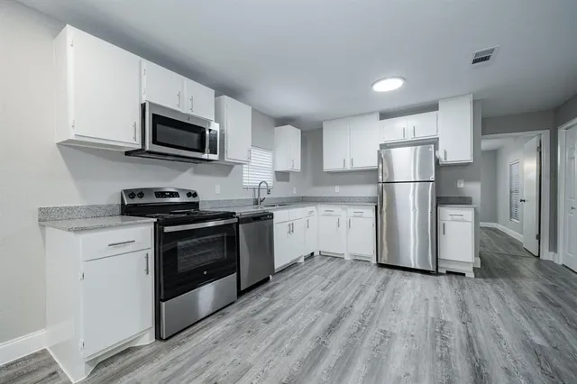 a kitchen with a refrigerator stove and white cabinets