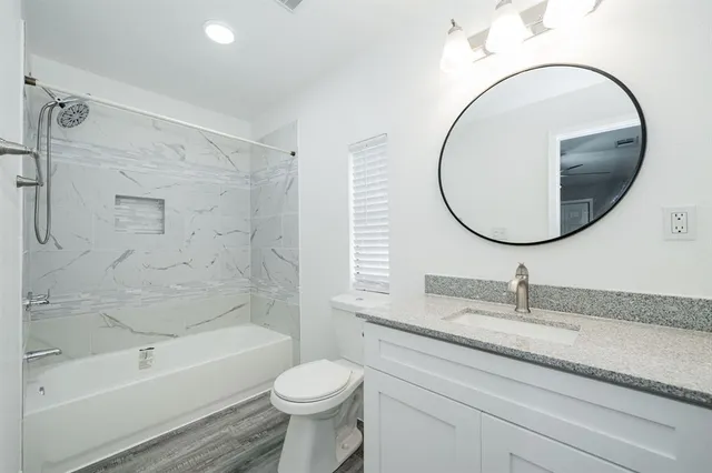 a bathroom with a granite countertop toilet a sink and a mirror