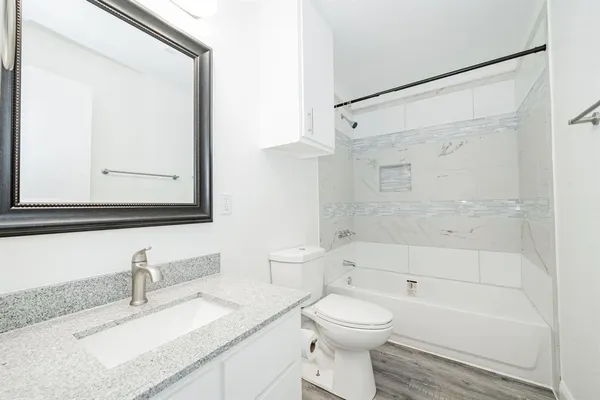 a bathroom with a granite countertop sink mirror vanity and toilet