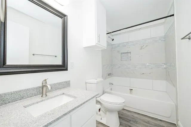 a bathroom with a granite countertop sink mirror vanity and toilet