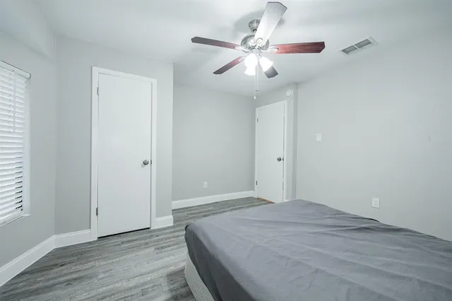 an empty room with wooden floor fan and windows