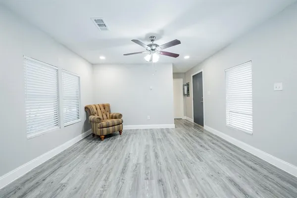 an empty room with windows and a ceiling fan
