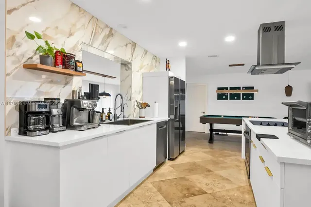 a kitchen with stainless steel appliances a sink a stove a refrigerator and cabinets