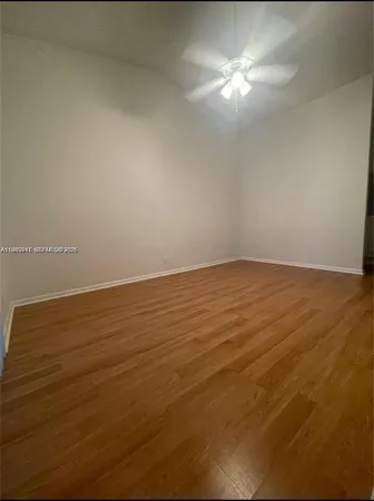 en empty room with wooden floor and fan