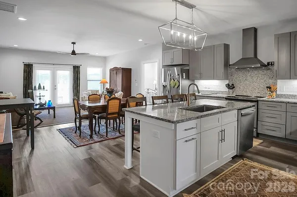 a kitchen with stainless steel appliances granite countertop a sink a stove and chairs