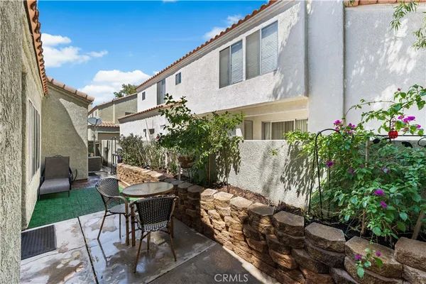 a backyard of a house with table and chairs with wooden fence