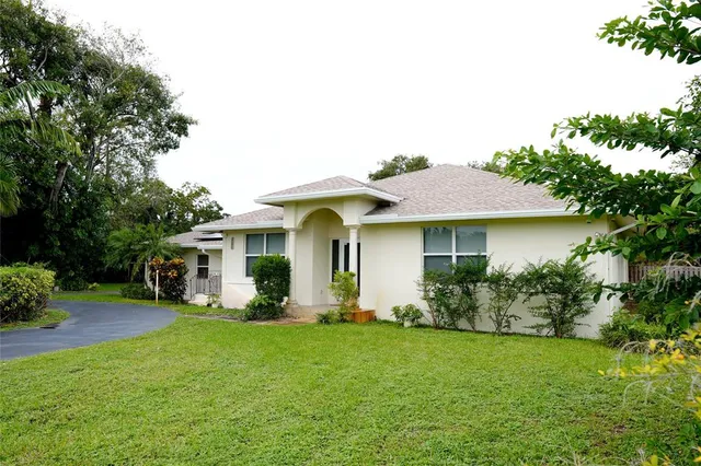 a front view of a house with a garden and trees