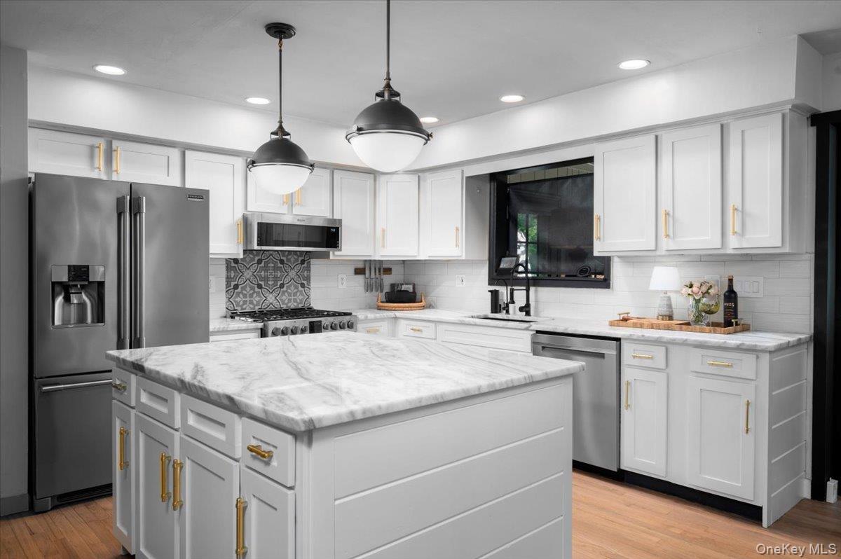 13 Jacks Pond Road Newburgh, NY 12550 - Photo 9 of 44 A stylish kitchen featuring a quartzite-topped center island, crisp white cabinetry with gold-tone hardware, recessed lighting, and a pair of pendant lights.