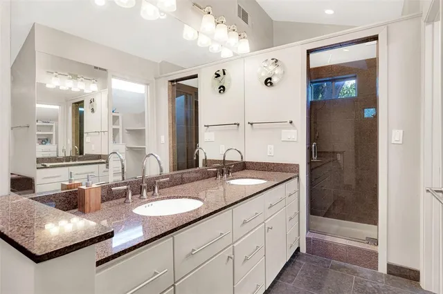 a bathroom with double vanity sinks a vanity two mirror and shower
