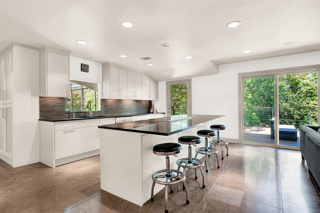 13311 Purple Sage Road Dallas, TX 75240 - Photo 4 of 31 a kitchen with stainless steel appliances granite countertop a stove top oven a sink a dining table and chairs with wooden floor