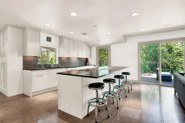 a kitchen with stainless steel appliances granite countertop a stove top oven a sink a dining table and chairs with wooden floor