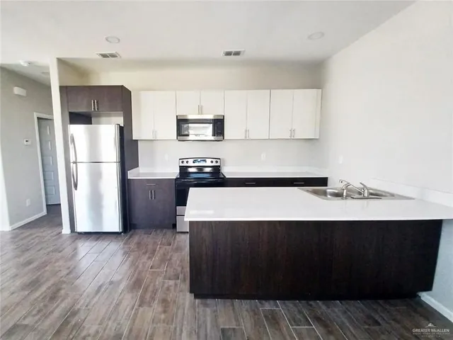 a kitchen with a sink a refrigerator and wooden floor