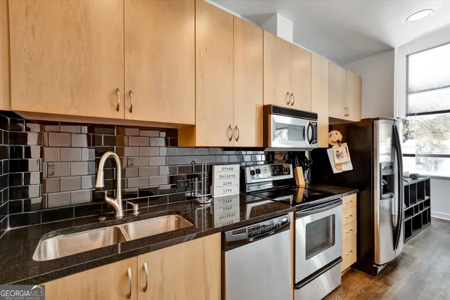 a kitchen with stainless steel appliances a sink a stove and cabinets