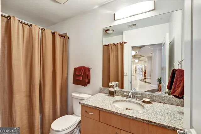 a bathroom with a granite countertop sink toilet mirror and shower