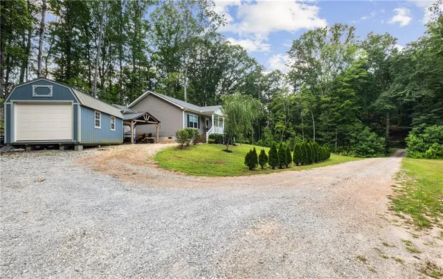 a view of a house with a small yard and large trees
