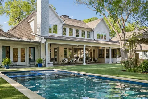 a view of a white building with a big yard and potted plants
