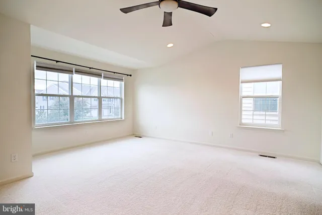 an empty room with windows and ceiling fan