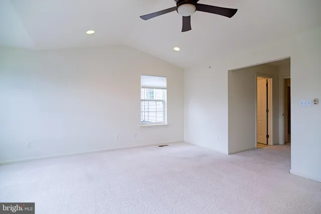 an empty room with a ceiling fan and windows