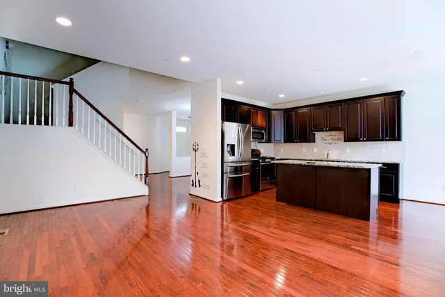 a kitchen with stainless steel appliances kitchen island granite countertop a refrigerator a stove a microwave oven a sink and dishwasher with wooden floor