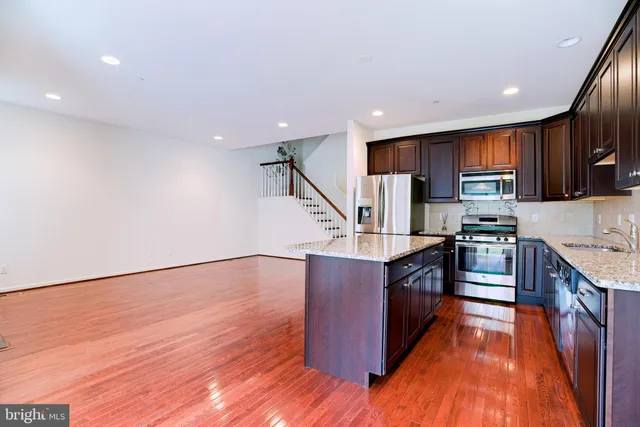 a large kitchen with stainless steel appliances granite countertop a stove and a wooden floors