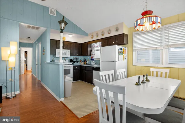 a kitchen with stainless steel appliances a refrigerator a stove a dining table and chairs