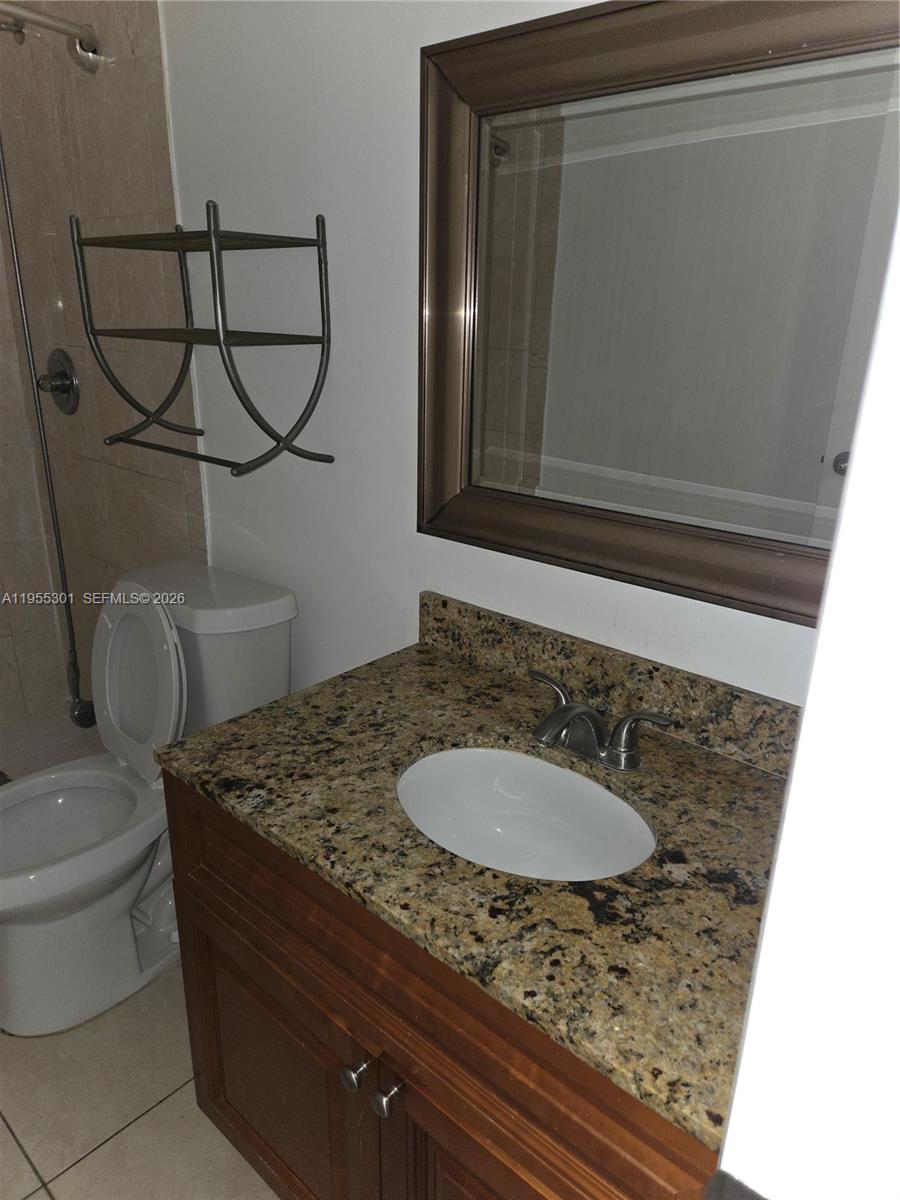 17901 Northwest 68th Avenue, Unit T106 Hialeah, FL 33015 - Photo 15 of 31 a bathroom with a granite countertop sink a toilet and mirror