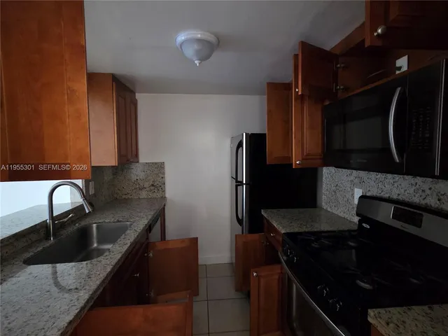 a kitchen with granite countertop a sink stove and refrigerator
