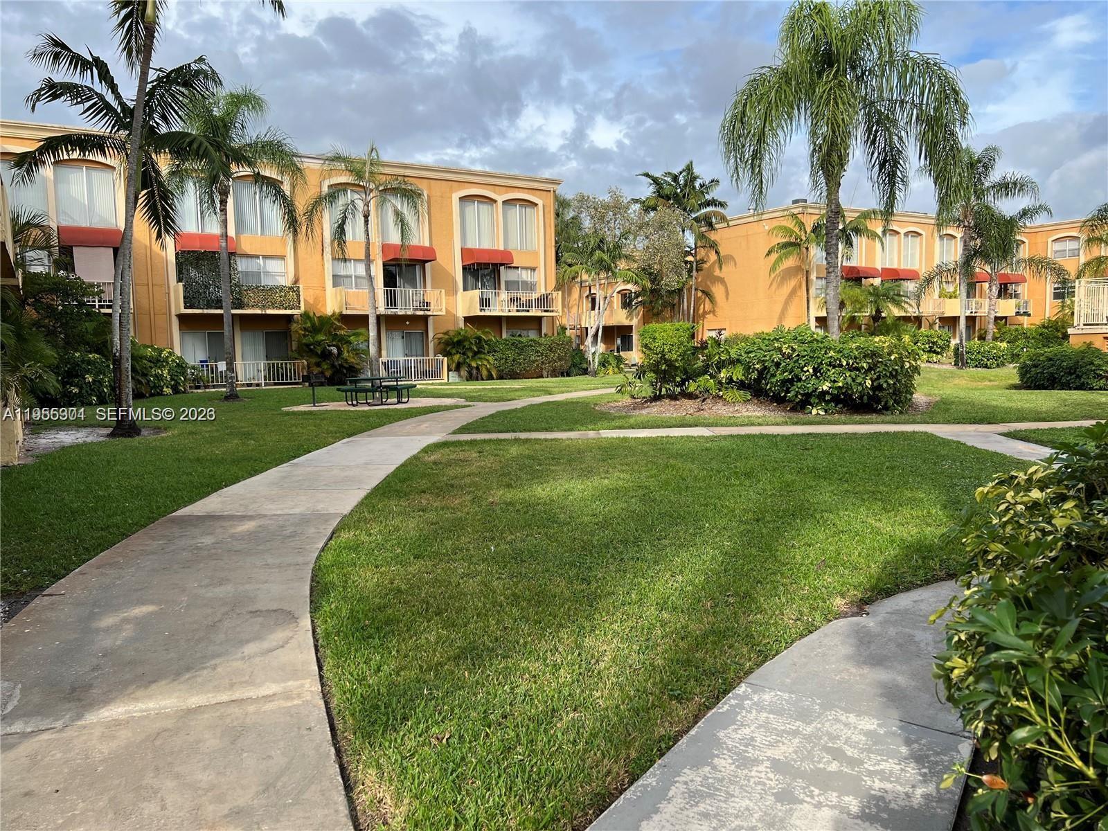 17901 Northwest 68th Avenue, Unit T106 Hialeah, FL 33015 - Photo 26 of 31 a front view of multi story residential apartment building with yard and green space