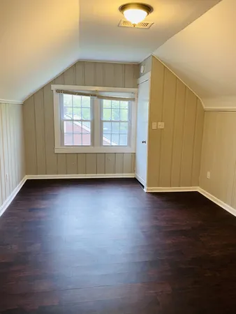 an empty room with wooden floor and windows with curtains