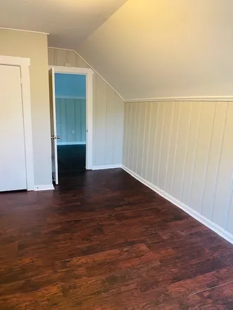 a view of an empty room with wooden floor and closet