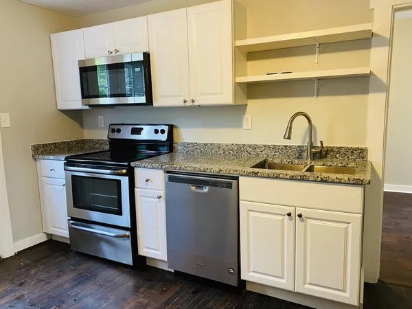 a kitchen with granite countertop white cabinets and appliances