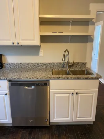 a kitchen with granite countertop white cabinets and a sink