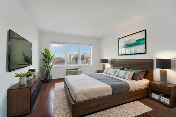 a bedroom with a bed a couch and a potted plant