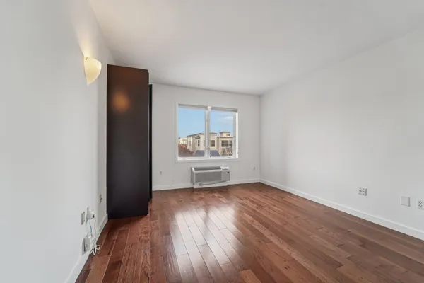 an empty room with wooden floor and windows