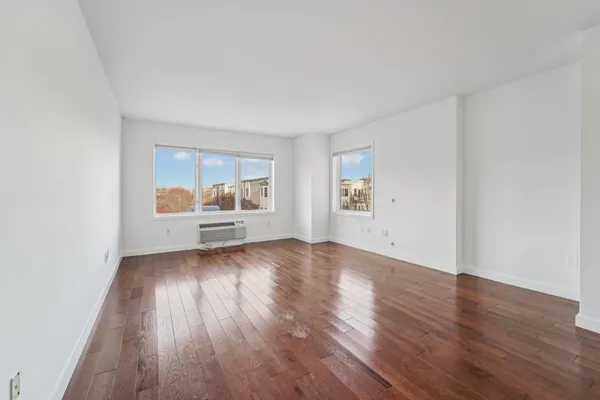 an empty room with wooden floor and window