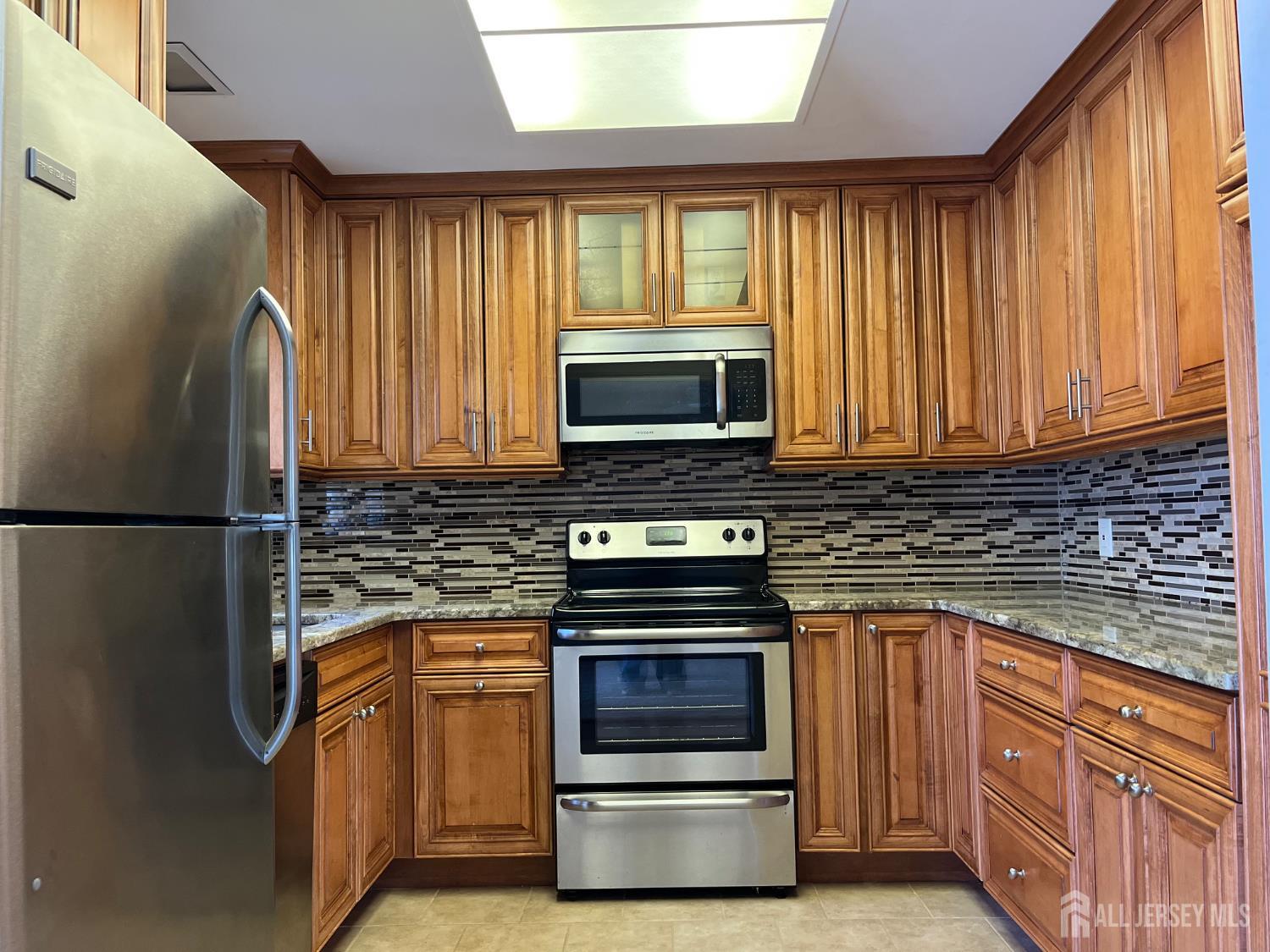 333 Newport Way, Unit C Monroe Township, NJ 08831 - Photo 12 of 17 a kitchen with granite countertop a refrigerator and a stove top oven