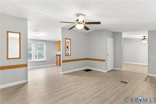an empty room with wooden floor ceiling fan and windows