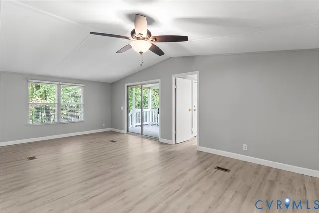 an empty room with wooden floor chandelier fan and windows
