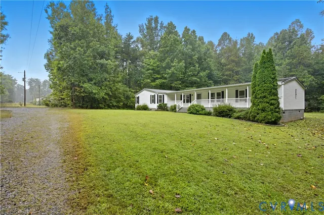 a view of a house with yard and trees in the background
