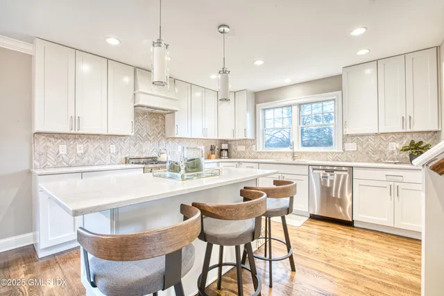 a kitchen with kitchen island granite countertop a sink cabinets and wooden floor
