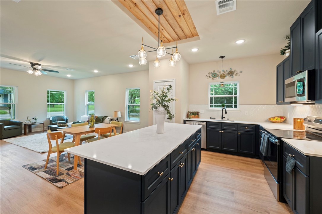 804 East 27th Street Bryan, TX 77803 - Photo 8 of 21 a large kitchen with kitchen island a stove a sink a dining table and chairs with wooden floor