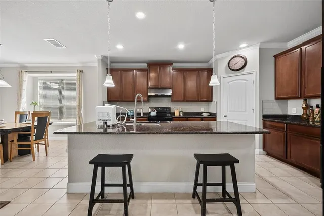 a kitchen with stainless steel appliances granite countertop a stove a sink a refrigerator and chairs