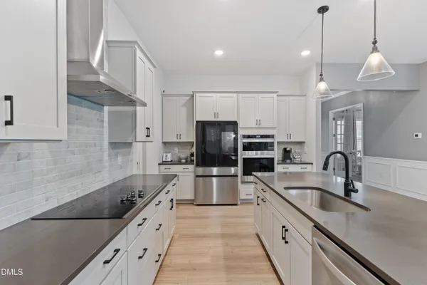 a kitchen with stainless steel appliances granite countertop a sink a stove a refrigerator cabinets and chairs