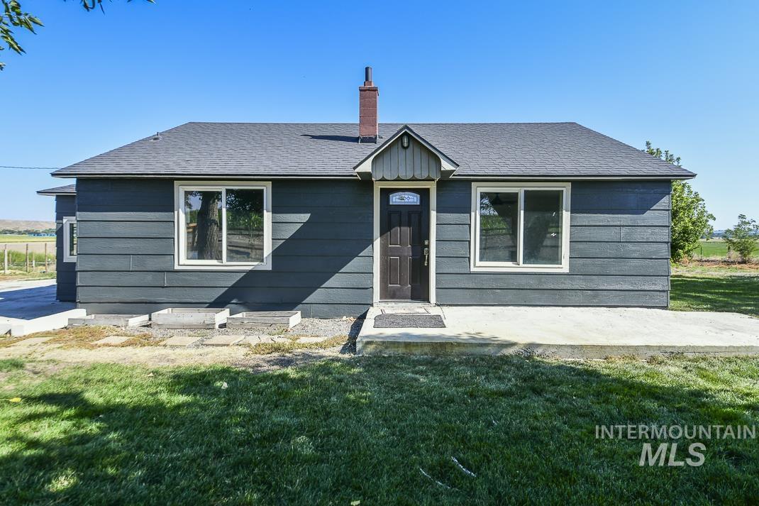 View of front of house with a front yard, roof with shingles, and a chimney