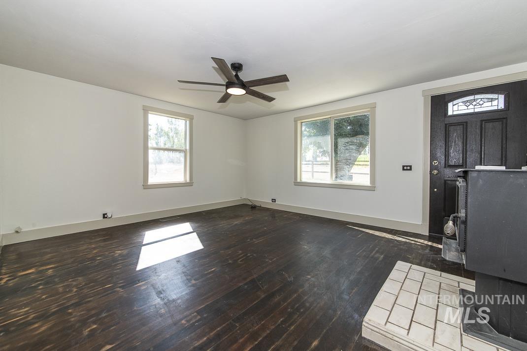 3432 West Pioneer Road Homedale, ID 83628 - Photo 9 of 21 Unfurnished living room with dark wood-type flooring, plenty of natural light, a wood stove, and ceiling fan