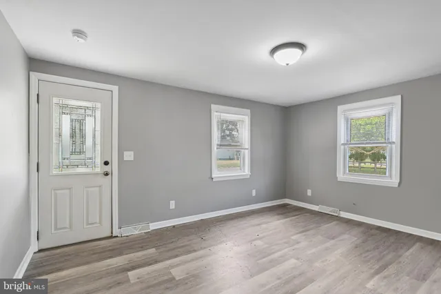 an empty room with wooden floor and windows