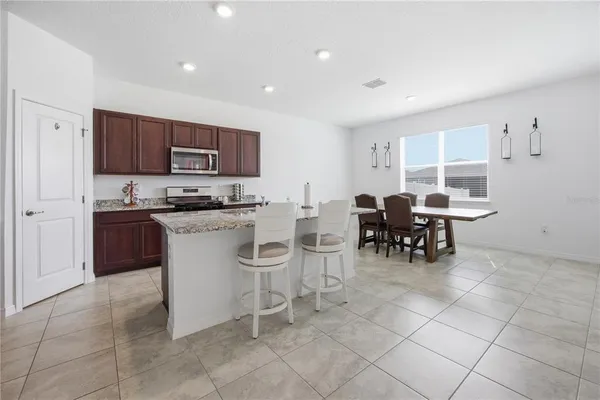 a kitchen with stainless steel appliances a stove a sink a dining table and chairs