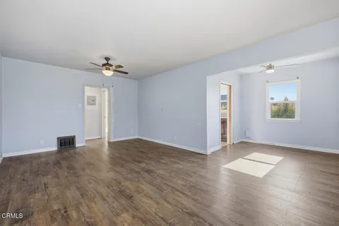 an empty room with wooden floor chandelier fan and windows