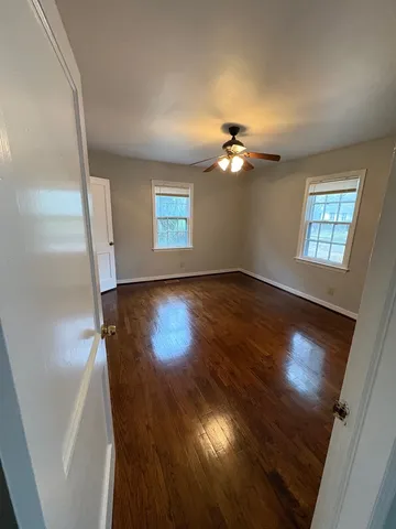 a view of an empty room with a window and wooden floor