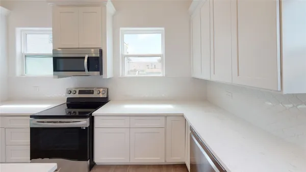 a kitchen with white cabinets and black appliances